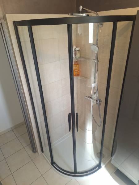 Installation d'une cabine de douche noire avec faïence beige dans une maison à Mesnils-sur-Iton